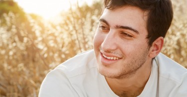 A young man sitting in a field relaxing and enjoying nature